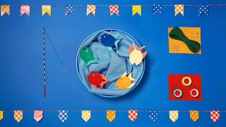 Peixinhos de papel coloridos em aquário feito com tecido azul, para brincadeira de pescaria em festa junina