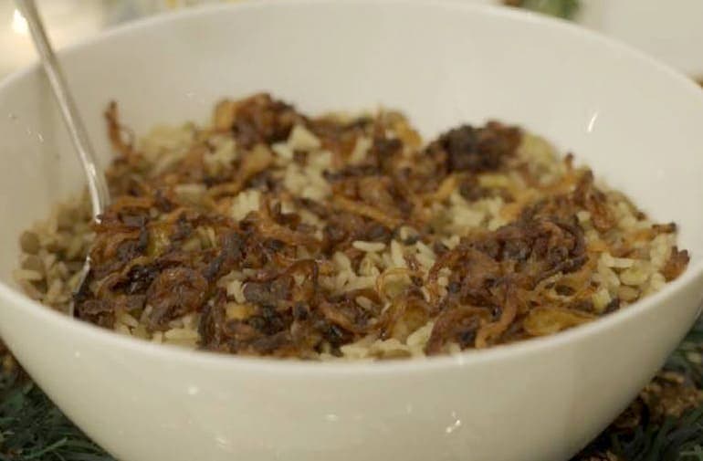 Arroz de lentilha com cebola frita caramelizada crocante, servido em recipiente branco de porcelana