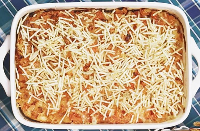 Cachorro-quente de forno em uma assadeira, coberto com molho, queijo derretido e batata palha Yoki