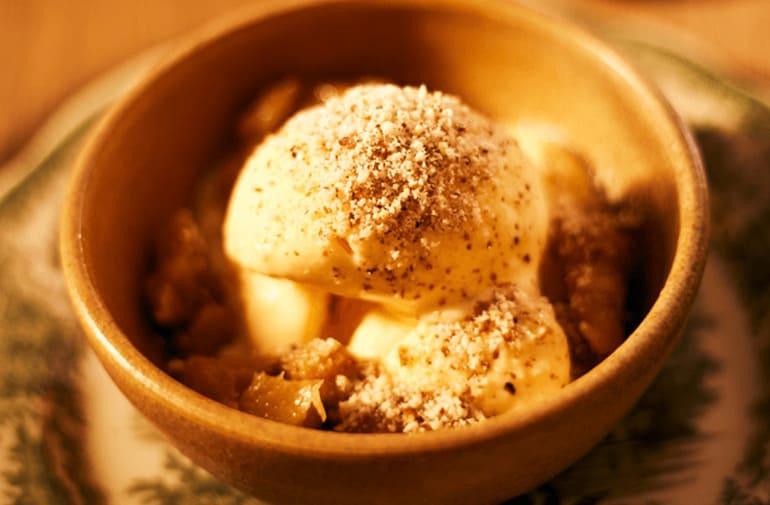 Bolas de sorvete de creme com abacaxi flambado e farofinha de amendoim em pote rústico de sobremesa