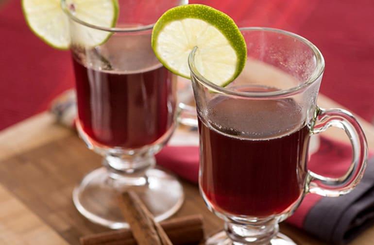 Vinho quente tradicional servido em copos de vidro com alça, decorados com rodela de limão