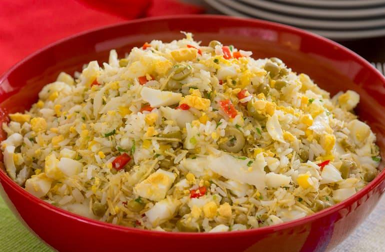 Arroz de bacalhau servido em tigela vermelha, refogado de bacalhau com ovos, azeitona e pimentão.