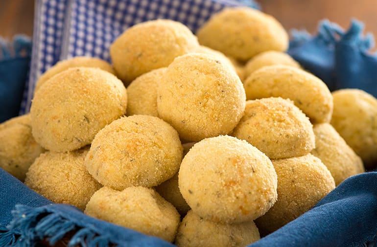 Bolinhos de tapioca assados, com casquinha crocante de farinha de rosca Yoki, servidos em cestinha com guardanapo azul
