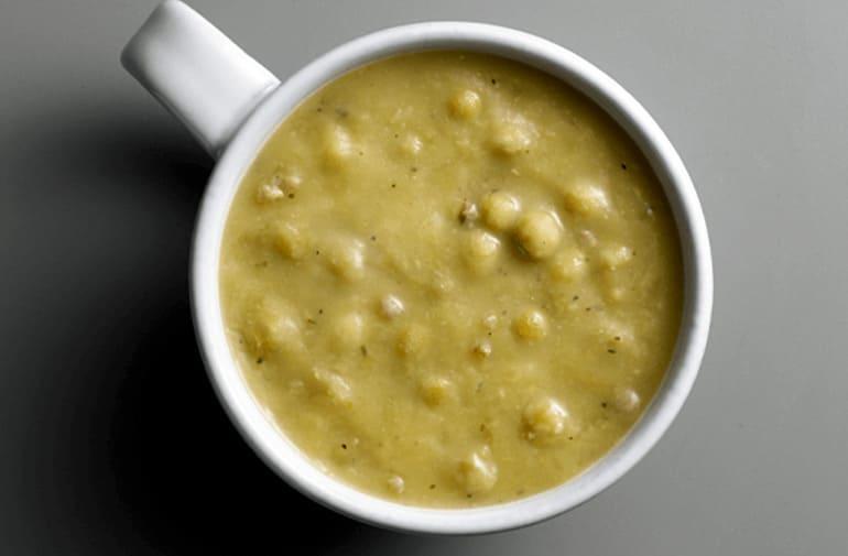Creme de ervilha com pedaços grandes, visto de cima em xícara de porcelana branca,