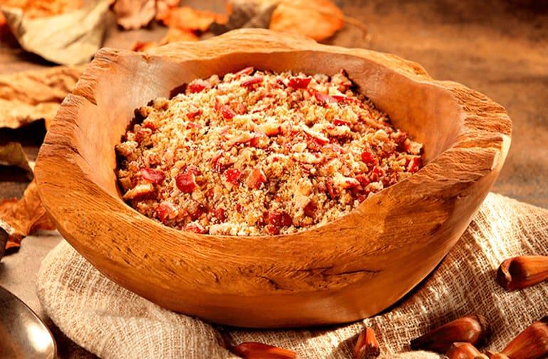 Farofa de pinhão cozido e triturado em uma tigela grossa de madeira rústica